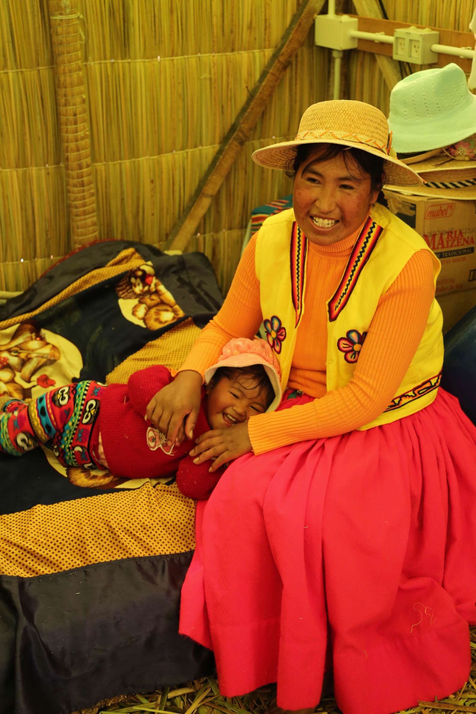 The inside of a hut on a floating island is sparse, but mother and child seem happy.